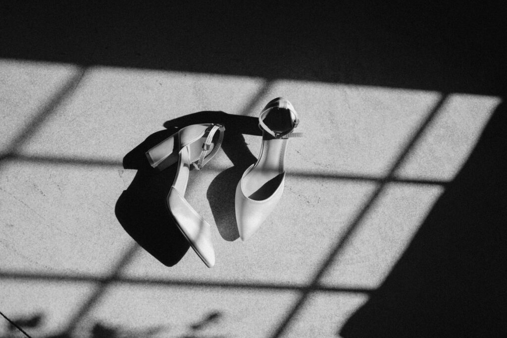 Black and white wedding detail photo of bride’s shoes sitting in soft window light. wedding photography