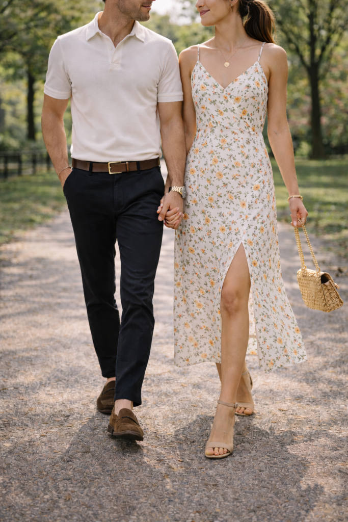 Couple posing for engagement photos with a floral maxi dress and heels, navy pants and white polo shirt. Engagement photo outfits