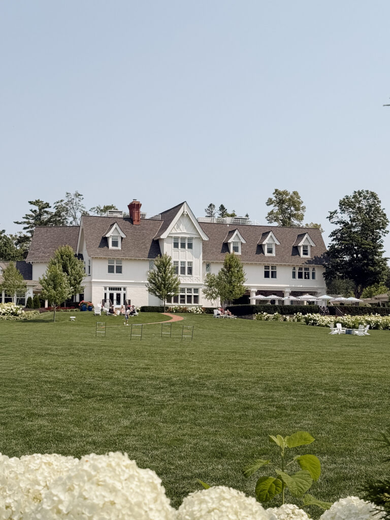 Hidden garden ceremony space at The Inn at Stonecliffe Mackinac Island wedding venue with wooden chairs and lush greenery. Wedding photographer