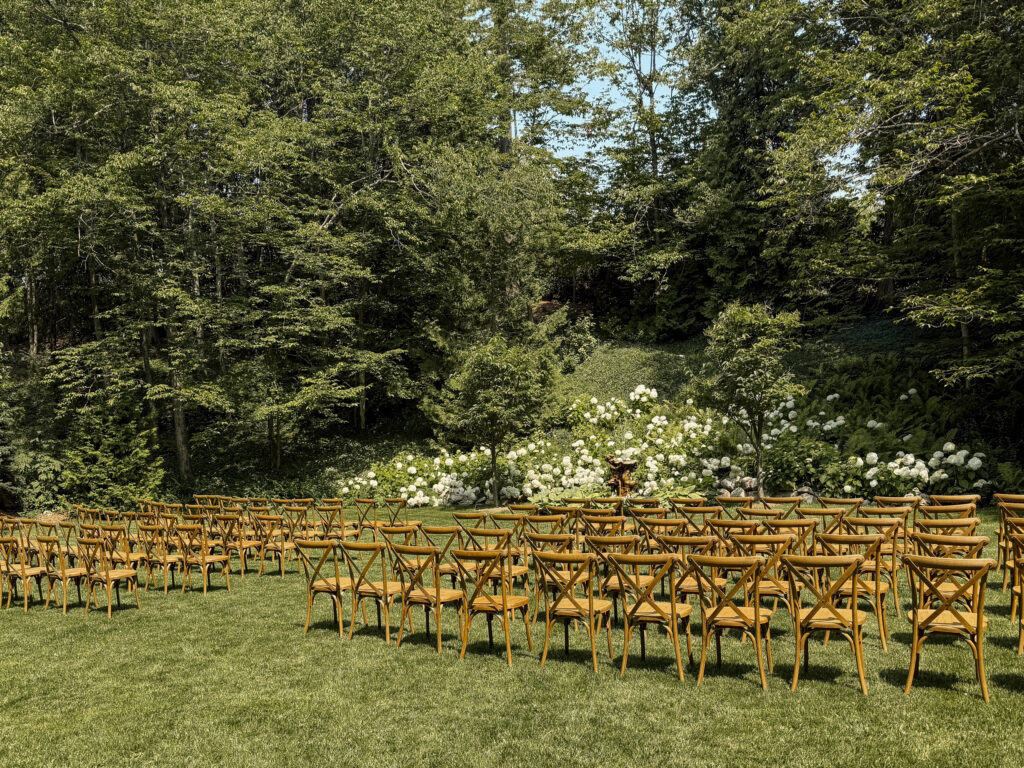 Hidden garden ceremony space at The Inn at Stonecliffe Mackinac Island wedding venue with wooden chairs and lush greenery. Wedding photographer