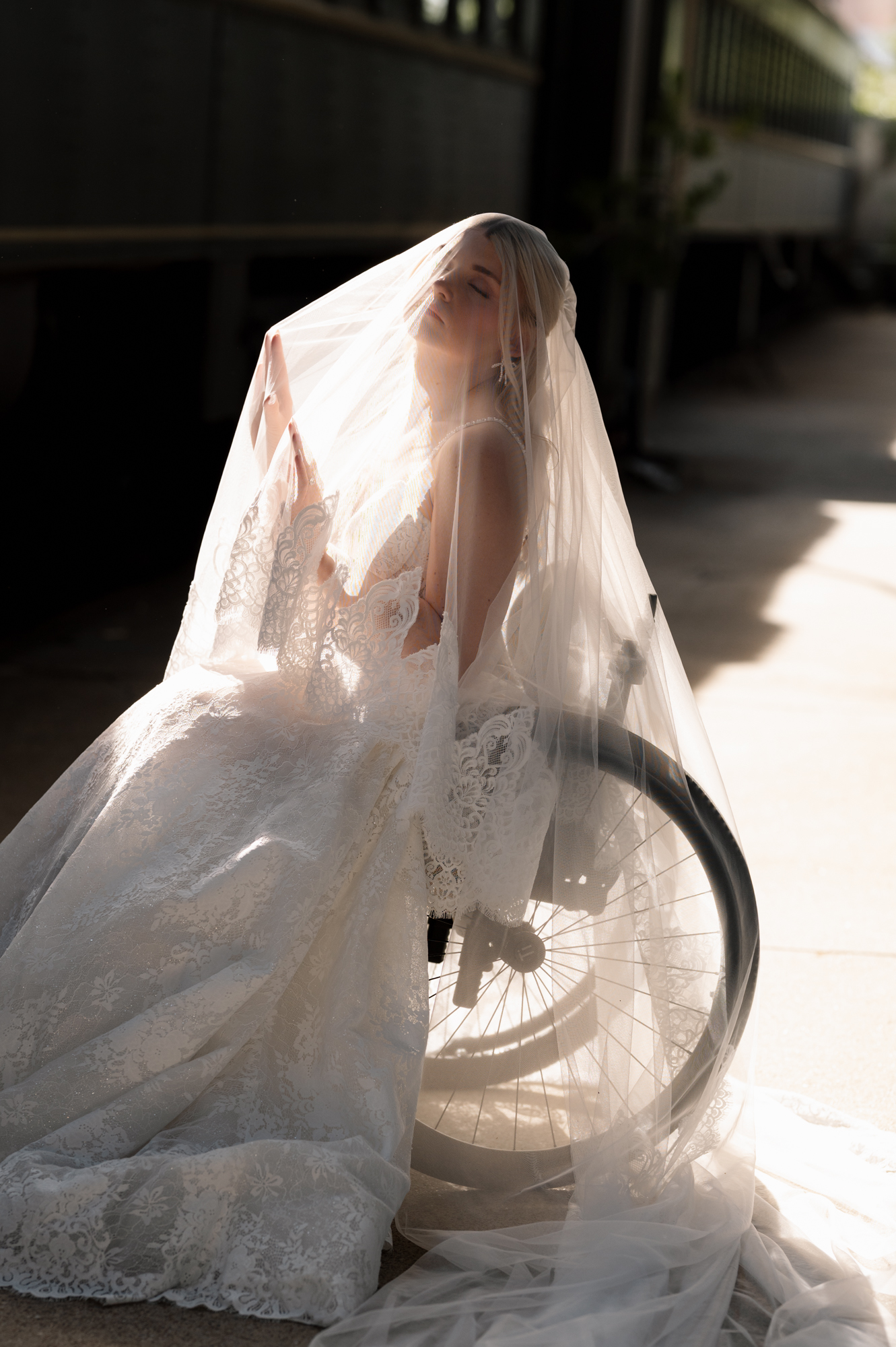 Bride in wheelchair wearing lace wedding dress and veil, captured in soft golden light with an elegant, editorial feel