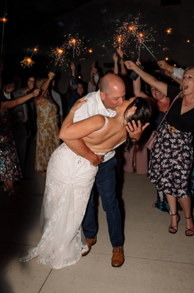 Bride and Groom in a sparkler exit kissing in a dip kiss after their wedding