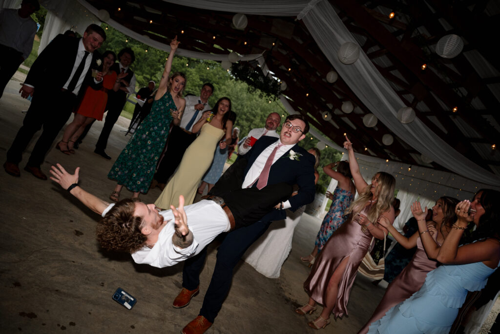 Man on the dance floor being spun around by best man