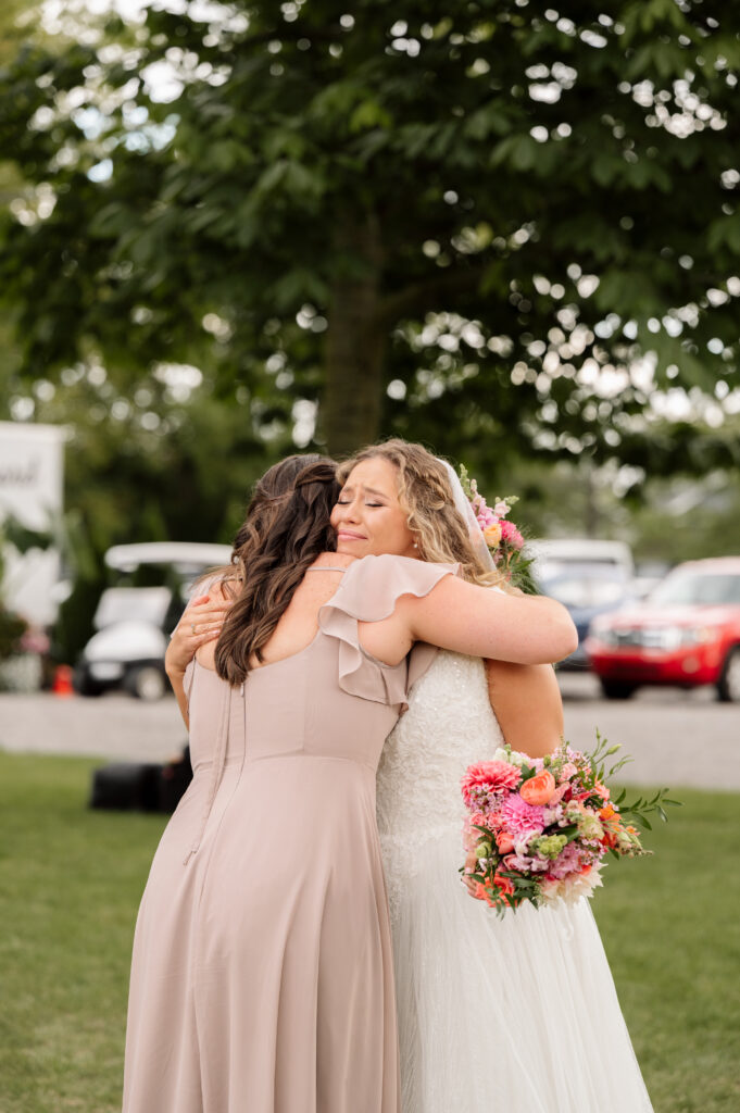 Bride and maid of honor hug an emotional hug after the ceremony.