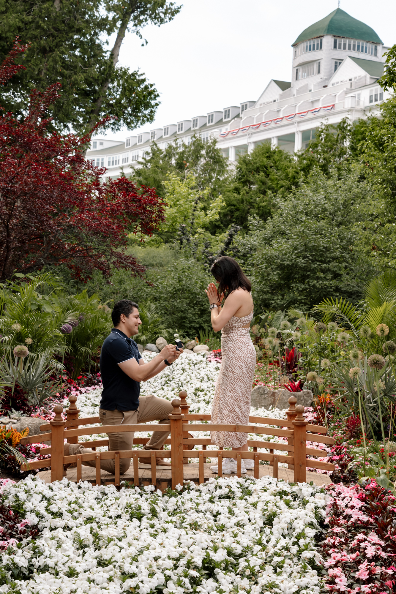 Couple sharing a surprise proposal in the Secret Garden at Grand Hotel on Mackinac Island, photographed by Mackinac Island proposal photographer Kali Britton Photo.