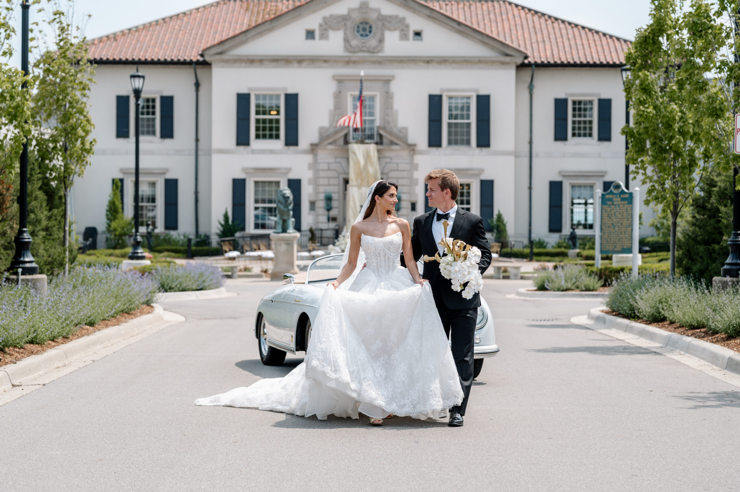 Luxury wedding bride and groom sitting in a vintage Porsche in front of a historic mansion during an elegant editorial style wedding photoshoot.